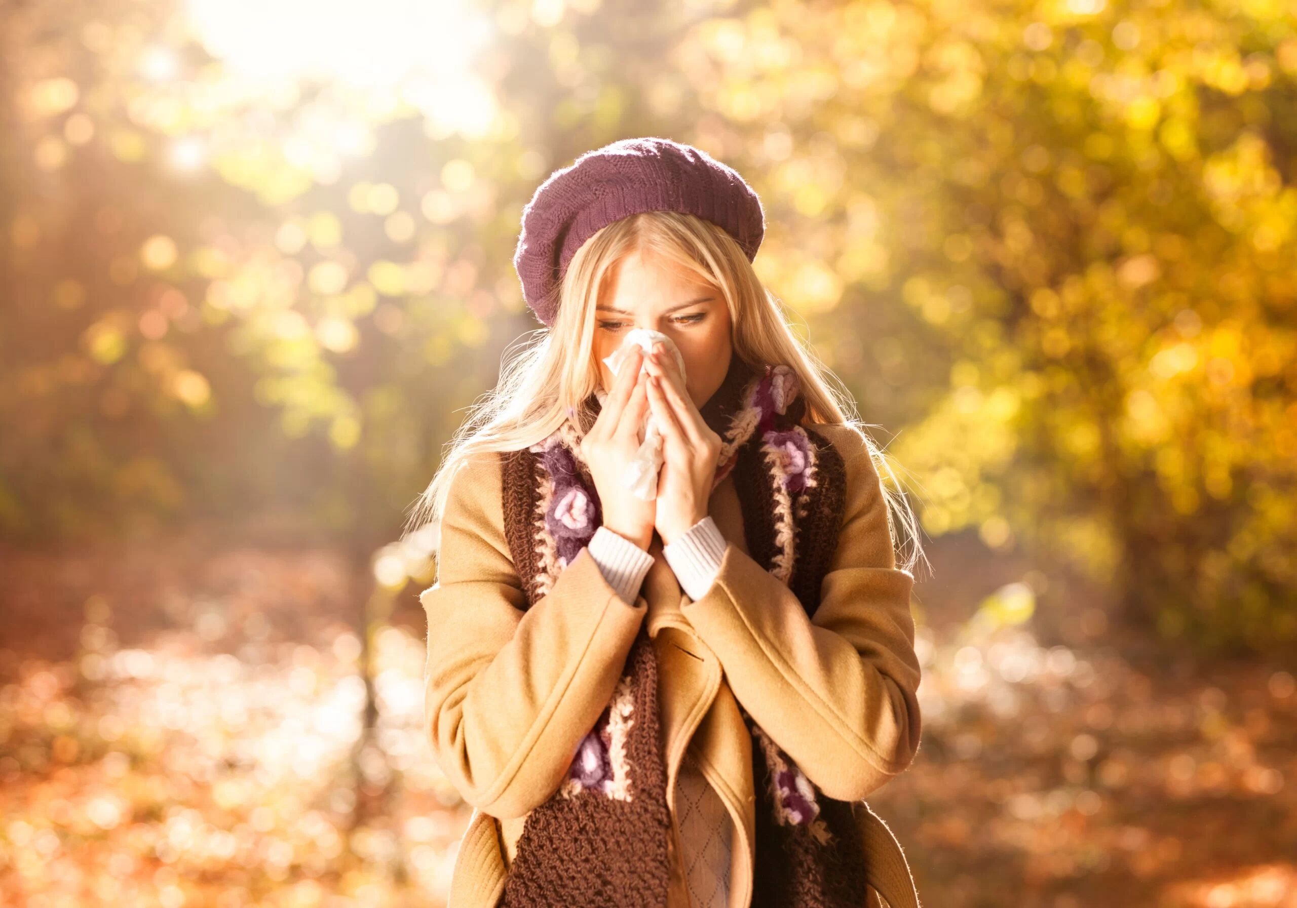 Aumentare le difese immunitarie: donna in autunno si soffia il naso